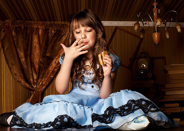 Little girl in a blue dress on the floor in a little room eat cake