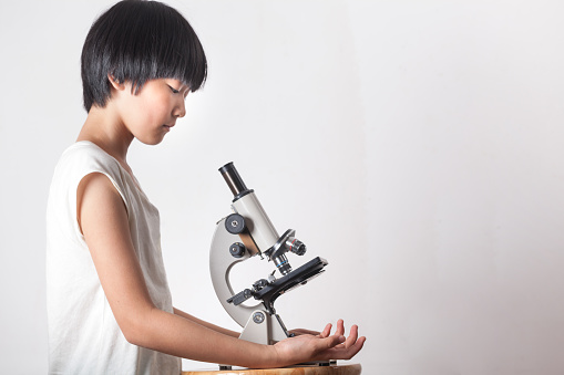 asian girl with microscope on white background