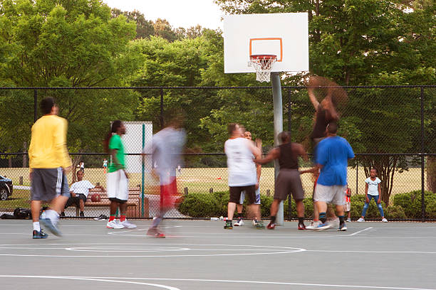 Motion Blur Of Men Playing Pickup Basketball On Playground Court Lawrenceville, GA, USA - May 27, 2016: Motion blur of young men playing a pickup game of basketball at a public park on May 27, 2016 in Lawrenceville, GA. asphalt basketball court stock pictures, royalty-free photos & images