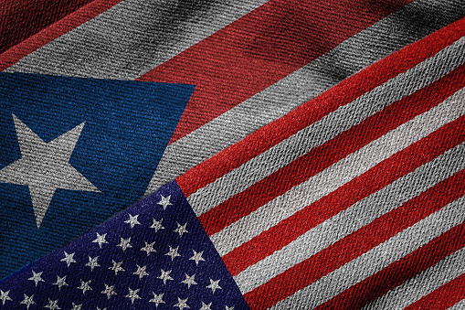 3D rendering of the flags of USA and Puerto Rico on woven fabric texture. Puerto Rico is a U.S. territory. Detailed textile pattern and grunge theme.