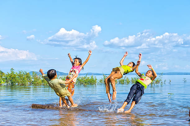 Dong Nai, Vietnam - November 15th, 2015: Children  jumping in lake afternoon with movements, flying directly into water exciting games childhood innocence rural areas in Dong Nai, Vietnam