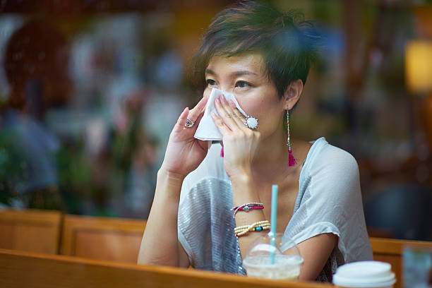 istock sick young woman blowing her nose 539356060