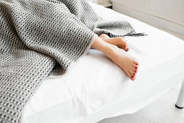 istock Woman feet under gray blanket sideview 539356332