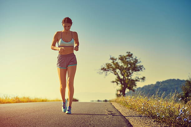 Running woman Beautiful fit woman in sport shorts running on a road at sunrise or sunset. Healthy lifestyle concept. Toned with warm instagram like filter. hot women working out pictures stock pictures, royalty-free photos & images