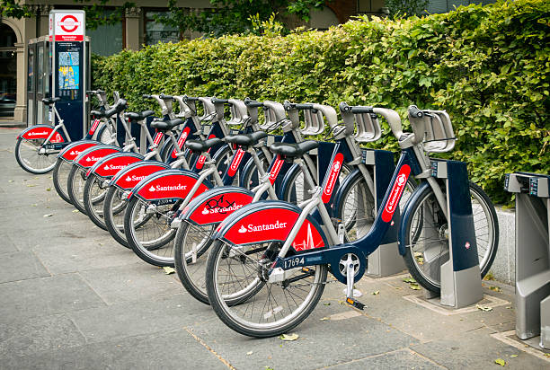 Santander 'Boris Bikes' London, England - June 10, 2015: A row of Santander cycle hire 'Boris Bikes' in a docking station in Bermondsey, South London. Originally, the bikes were sponsored by Barclays but the sponsorship is now by Santander. bicycle docking station stock pictures, royalty-free photos & images