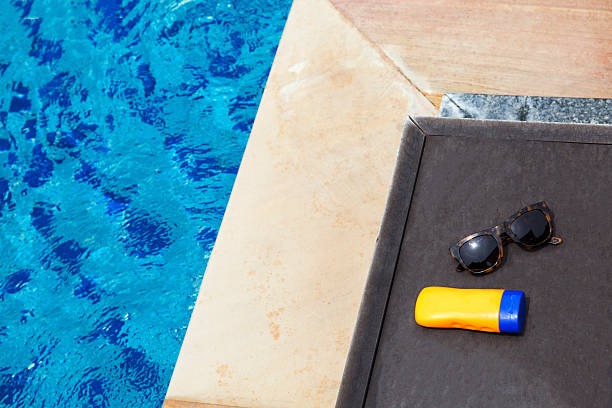 istock Top view of sunglasses and sun lotion on poolside 539363052