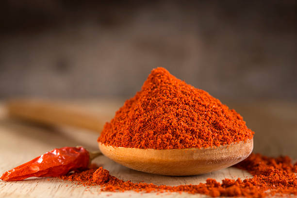 cucchiaio pieno di paprika rossa caldo in polvere - paprica foto e immagini stock