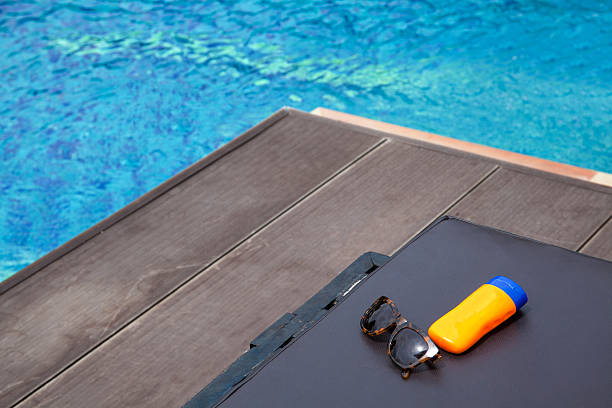 Top view of sunglasses and sun lotion on poolside