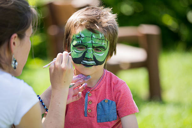 Beautiful little kid boy with face painted with animal or cat, on a birthday party. happy child having fun. Activity for kids on birthday celebration part, face painting, fun and happiness