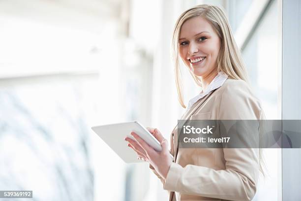 Portrait Of Smiling Young Businesswoman Using Digital Tablet In Office Stock Photo - Download Image Now