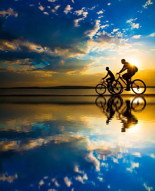 Photo of Sporty friends.  bicycle on sunset.