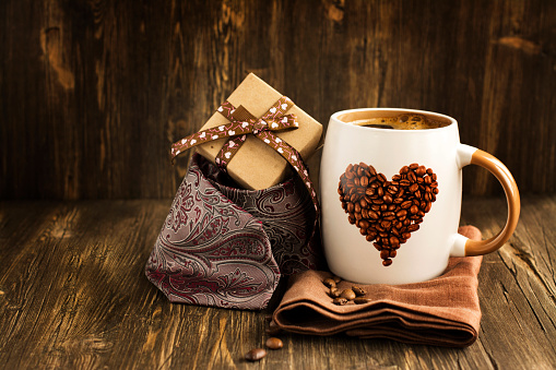 Happy Fathers Day Card. Mug of coffee, gift box and tie over wooden table. Vintage style. Toned image. Selective focus