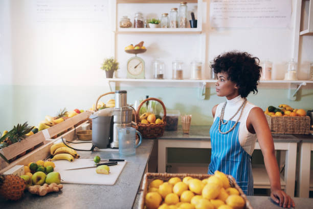 istock Young female bartender standing at juice bar counter 539370034