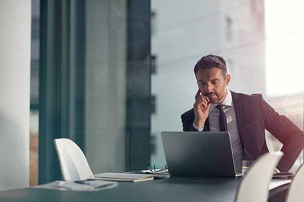 Focused on meeting his deadline Shot of a businessman working on a laptop in an office laptop businessman business men stock pictures, royalty-free photos & images