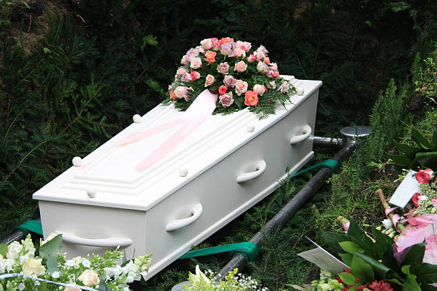 White coffin with pink sympathy flowers stock photo