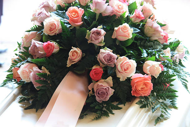 pink sympathy flowers on a white coffin stock photo