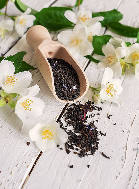 mesurant dégagée avec thé noir frais et des fleurs de jasmin - jasmine tea black tea tea drink photos et images de collection