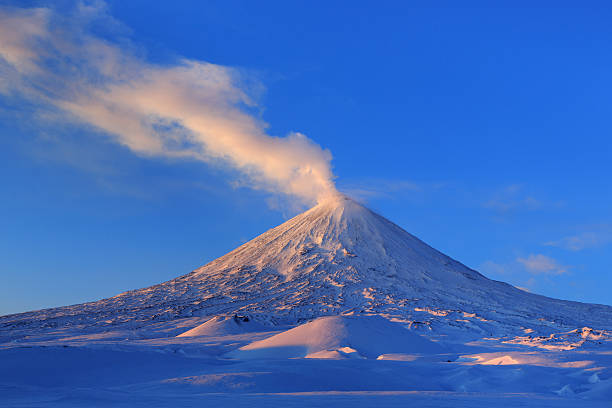 Beautiful winter volcanic landscape of Kamchatka Peninsula: view of eruption active Klyuchevskoy Volcano at sunrise. Eurasia, Russia, Far East, Kamchatka Region, Klyuchevskaya Group of Volcanoes.