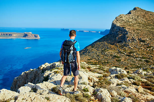 istock male traveler with backpack runs on the cliff against sea 539451876