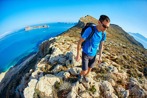istock male traveler with backpack runs on the cliff against sea 539452236