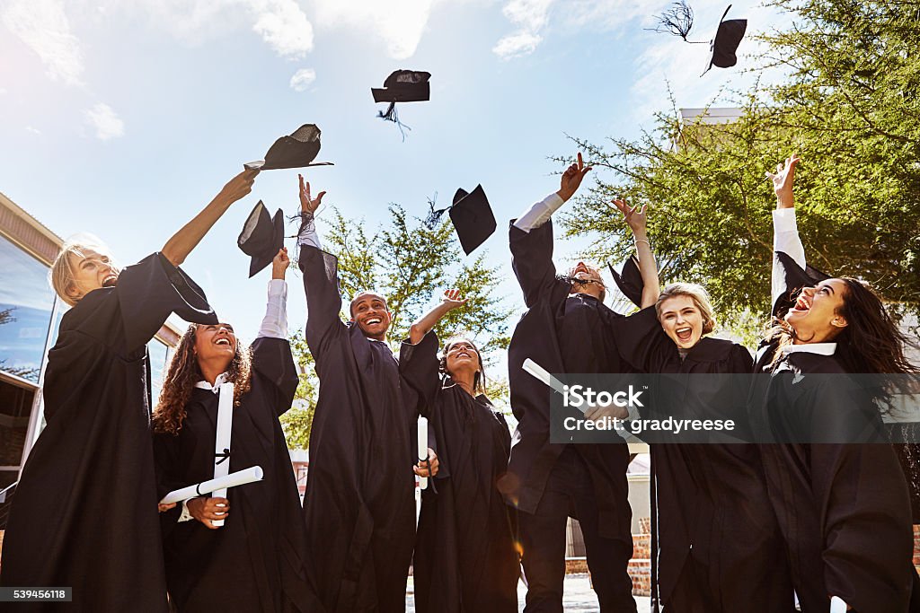 Hats off to graduating! Shot of a group of smiling university students cheering and throwing their caps outside on graduation day Graduation Stock Photo