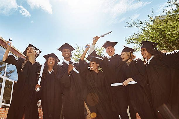 Celebrating graduation Portrait of a group of smiling university students holding their diplomas outside on graduation day graduation photos stock pictures, royalty-free photos & images