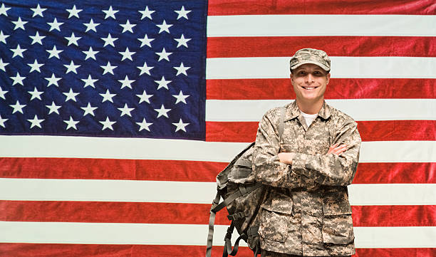 istock Smiling soldier standing in front of flag 539461652