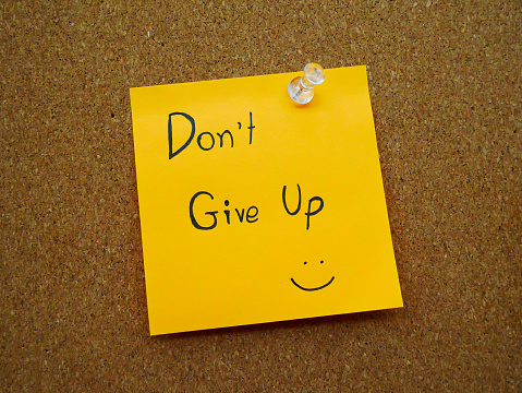 Don't give up in post note on wooden board