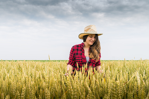 Happy woman farmer in a field of wheat