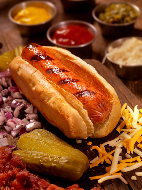 hot-dog mit allen zutaten - cheese focus on foreground on top of portion stock-fotos und bilder