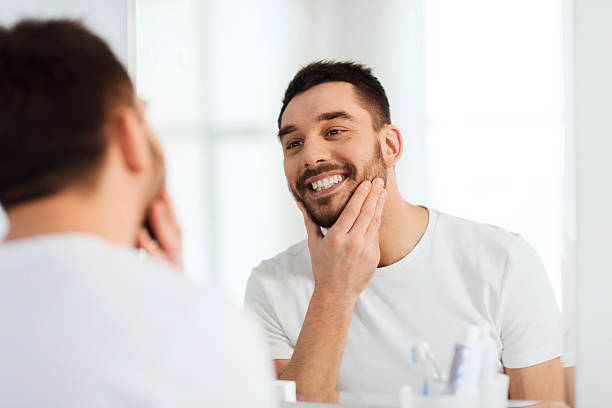 istock happy young man looking to mirror at home bathroom 539469392