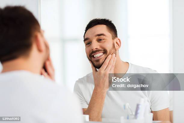 Happy Young Man Looking To Mirror At Home Bathroom Stock Photo - Download Image Now - Men, Mirror - Object, Looking