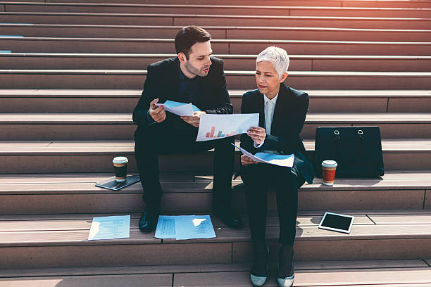 istock Businesspeople sitting on Stairs And Examining Paperwork. 539469674