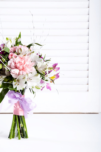 Pastel bouquet from pink and purple gillyflowers and white alstroemeria on white shutter background