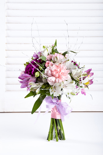 Pastel bouquet from pink and purple gillyflowers and alstroemeria on white shutter background