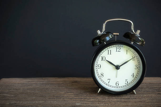 istock Alarm clock on wood with a black background 539470888