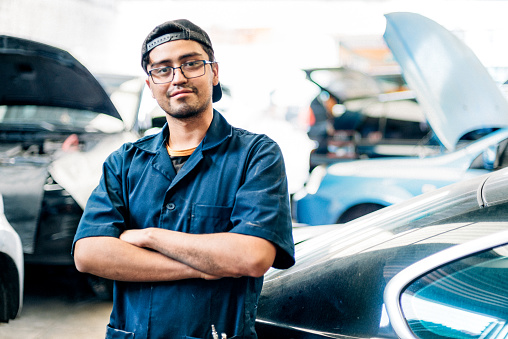 Portrait of a Mexican car mechanic in auto repair shop.