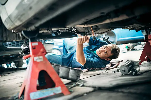 Low angle view of a mechanic working under a vehicle.