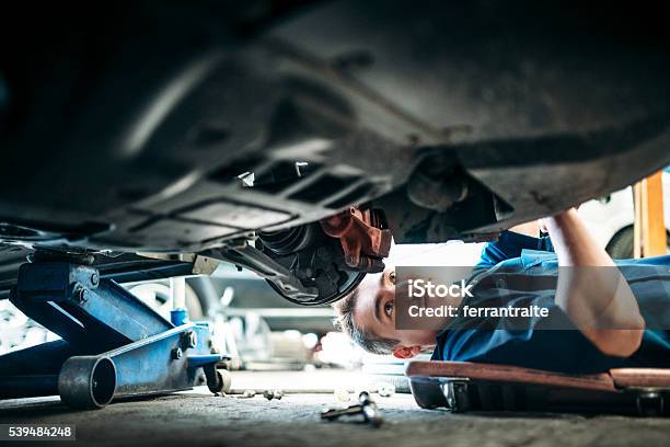 Mecánico Trabajando Bajo Auto Vehículo Foto de stock y más banco de imágenes de Coche - Coche, Reparar, Garaje de reparación