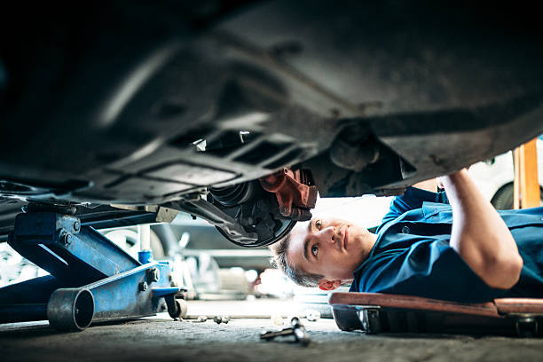 mécanicien travaillant sous voiture du véhicule - auto repair shop photos et images de collection