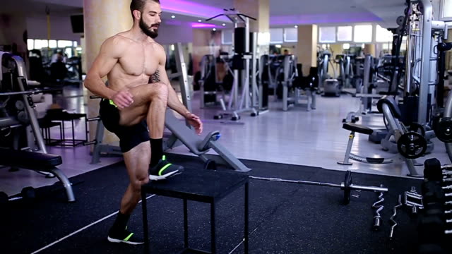 Fit man doing box jumps in gym