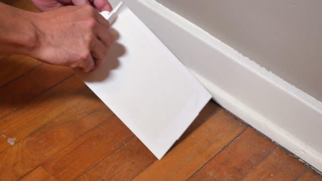 Man Placing Sticky Rat Trap on Household Floor
