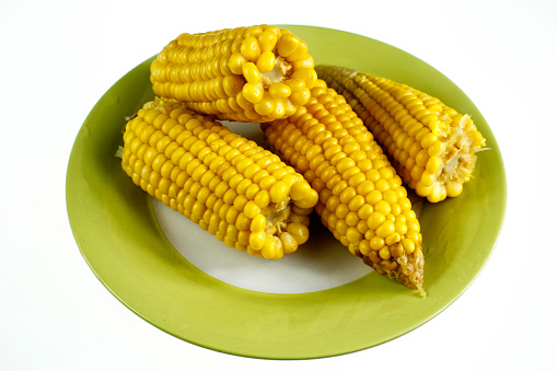 Steamed sweetcorn on the cob with butter served on plate