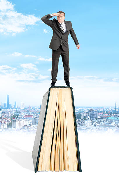 istock Businessman standing on book and looking away 539641496