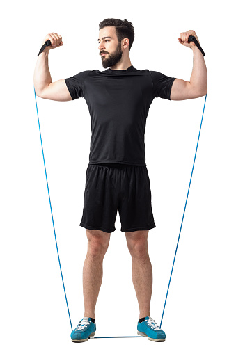Young athlete doing arms and shoulders exercise with resistance rubber elastic bands. Full body length isolated over white studio background