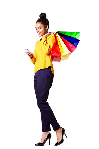 Full body portrait of african woman with shopping bags using mobile phone on white background