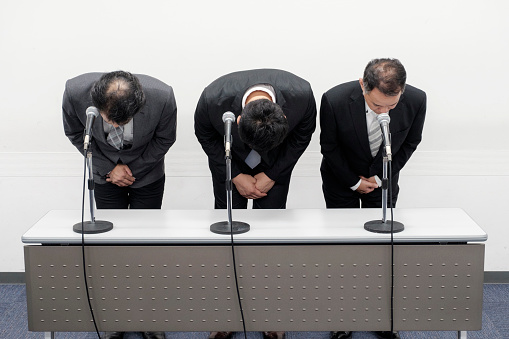A group of Japanese business people bowing to apologize as a form of shazaikaiken. Taken on location in Kyoto, Japan.