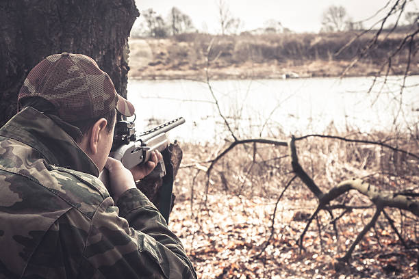 Hunter man with shotgun aiming  to make shot during hunt