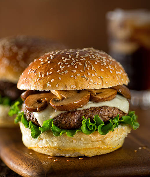 Mushroom Swiss Burger A delicious gourmet hamburger topped with swiss cheese and fried mushrooms on a rosemary sesame seed bun. swiss culture photos stock pictures, royalty-free photos & images