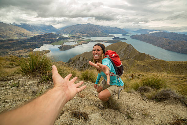 Hiker assists teammate on mountain top Young woman hiking pulls out his hand to get assistance from teammate. clambering photos stock pictures, royalty-free photos & images